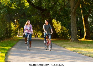 A man and a woman with their bicycles on a bike path in an outdoor park setting. - Powered by Shutterstock