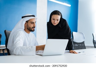 Man And Woman With Traditional Clothes Working In A Business Office Of Dubai. Portraits Of  Successful Entrepreneurs Businessman And Businesswoman In Formal Emirates Outfits. Concept About Middle East