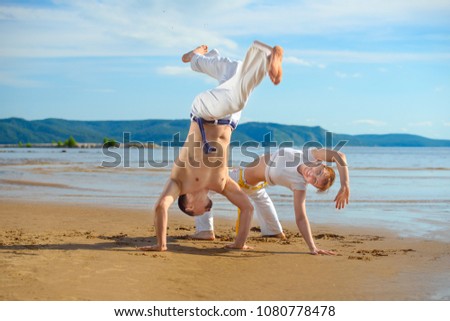 A man and a woman to train capoeira on the beach - concept about people, lifestyle and sport