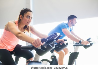 Man And Woman Using Cycling Exercise Bikes At The Gym