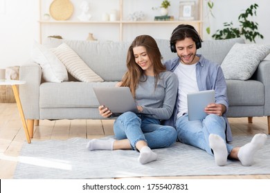 Man and woman using gadgets laptop, digital tablet, wireless headset while spending weekend tohether at home, copy space - Shutterstock ID 1755407831