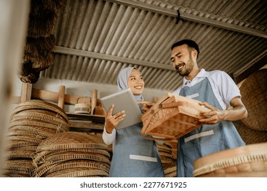 man and woman using tablet pc while working in their traditional product shop