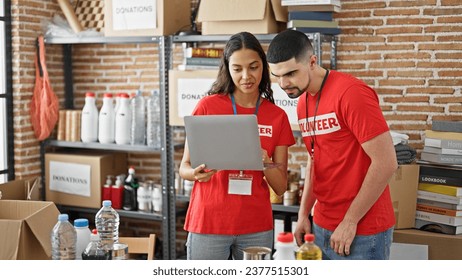 Man and woman volunteers smiling, working on laptop at charity center, standing together in service for community - Powered by Shutterstock