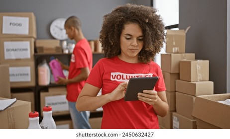 Man and woman volunteers working together, serious faces focused on touchpad at the community charity center, making altruism beautiful - Powered by Shutterstock