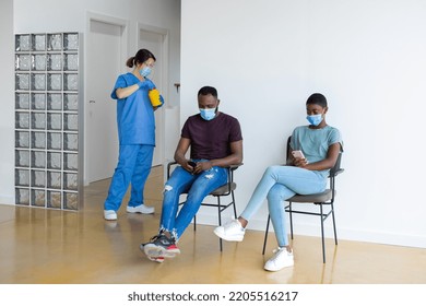 Man And Woman In Waiting Room Of A Hospital, Using Mobile Phone.