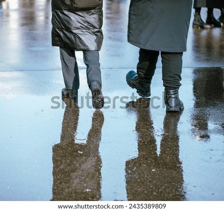 A man and a woman are walking through a puddle on a cold winter day.