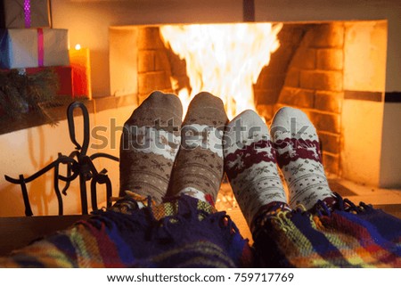 Man and woman in warm knitted socks in front of the fireplace