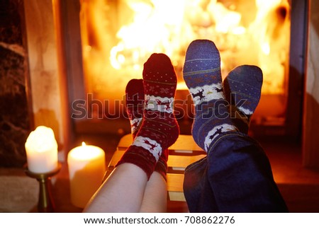 Man and woman in warm socks near fireplace. Cozy romantic evening for two or Christmas celebration concept