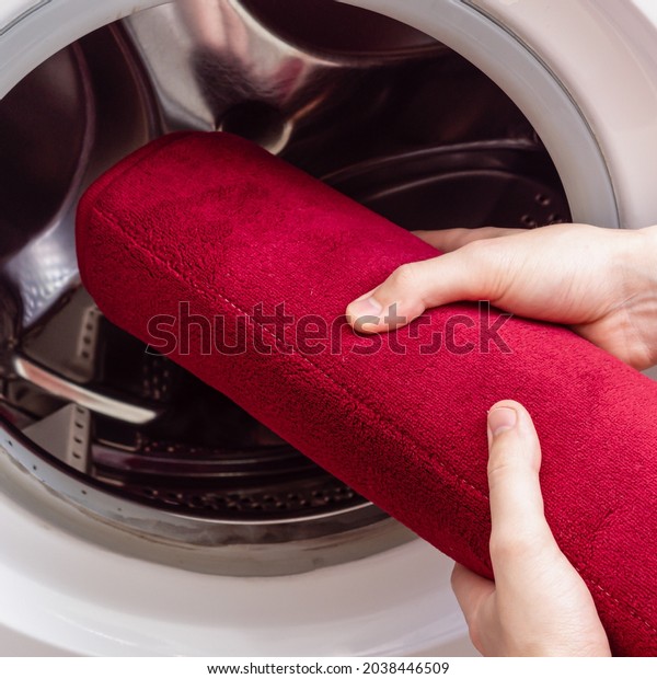 Man or woman washes red bath mat. Washing carpet\
in washing machine