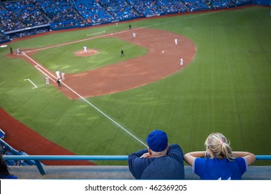 Man And Woman Watching A Baseball Game On The Opening Pitch