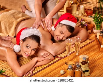 Man and woman wearing Christmas hat having massage. Concept Xmas spa.