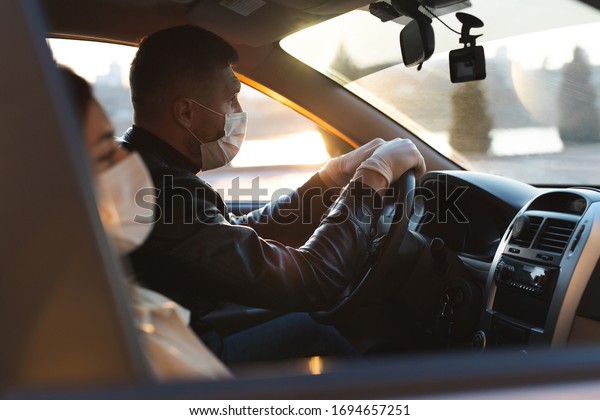 A man and a woman\
wearing medical masks and rubber gloves to protect themselves from\
bacteria and viruses while driving a car. masked men in the car.\
coronavirus, covid-19