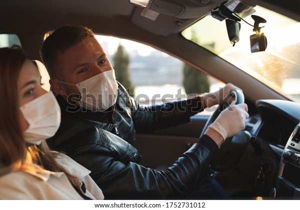 A man and a woman\
wearing medical masks and rubber gloves to protect themselves from\
bacteria and viruses while driving a car. masked men in the car.\
coronavirus, covid-19.