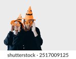 Man And Woman Wearing Witch Hats And Funny Glasses Making Faces Isolated On White Background. Couple Wearing Halloween Costumes And Posing. Halloween Party Concept