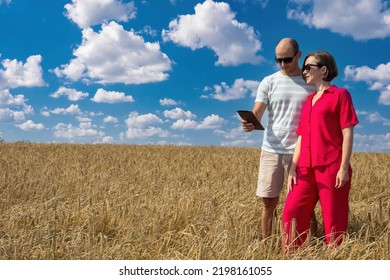 Man And Woman In Wheat Field. People And Agricultural Landscape. Guy And Girl Are Holding Tablet. Agricultural Business Owners. Concept Agronomists Check Harvest. Agricultural Company Managers