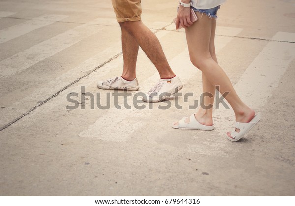 man and woman in white casual shoes crossing the\
street on the way.
