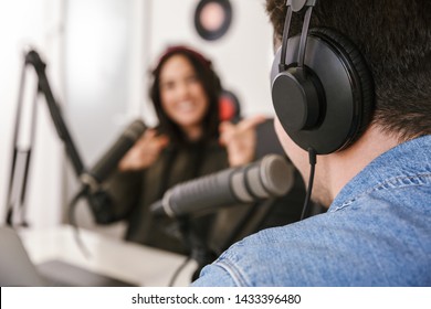 Man and woman in white shirts podcasters interview each other for radio podcast - Shutterstock ID 1433396480