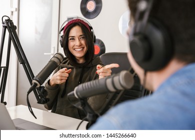 Man and woman in white shirts podcasters interview each other for radio podcast - Shutterstock ID 1445266640