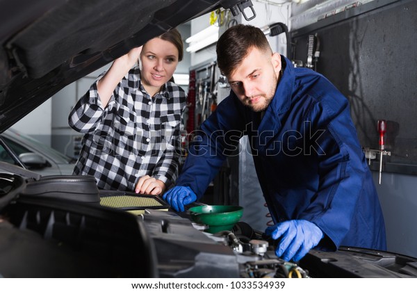 Man and woman workers are replacing the oil in\
the car in workshop\
