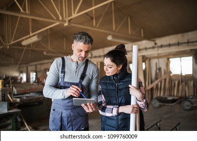 Man And Woman Workers With Tablet In The Carpentry Workshop.