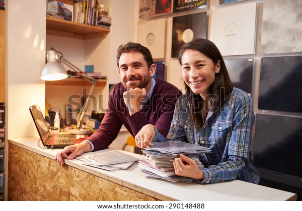 Man\
and woman working behind the counter at a record\
shop