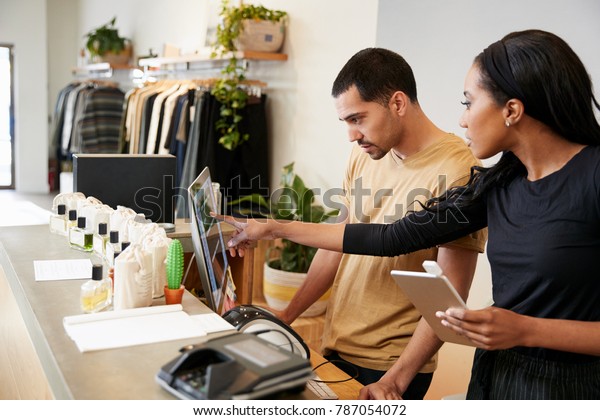 Man and woman working behind the counter in a\
clothing store