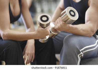 A Man And Woman Working Out At The Gym With Dumbbell Weights