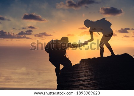 Man and woman working as a team climbing up a mountain. 