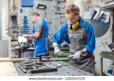 Man and woman working together in metal workshop with their tools