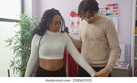 Man and woman working together in a tailor shop, measuring a garment with tape, showcasing teamwork and fashion design skills. - Powered by Shutterstock