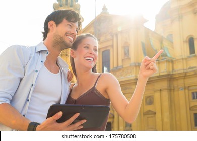 Man and woman or young couple making trip as tourists in Munich at the Odeon Church with city map on the tablet computer for navigation - Powered by Shutterstock