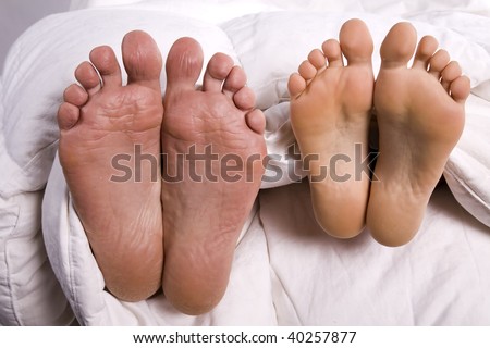 A man and woman's feet coming out from under the covers.