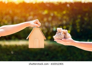 A man and women hand holding a home model and money bag a put together in the public park. buying or loans for real estate concept. - Shutterstock ID 610312301