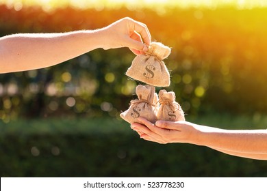 A man and a women hands hold a money bags in the public park for loans to planned investment in the future concept. - Shutterstock ID 523778230