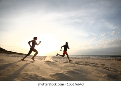 Man And Women Running On Beach At Sunset