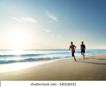 Man And Women Running On Tropical Beach At Sunset