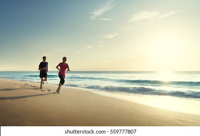 Man And Women Running On Tropical Beach At Sunset