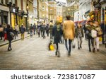 Man & women shopping on busy London high street with Christmas lights