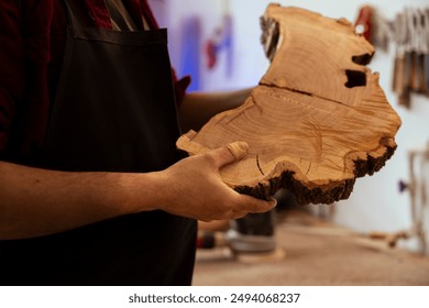 Man in woodworking shop inspecting lumber piece before assembling furniture, checking for scratches. Cabinetmaker evaluating timber block, ensuring it meets quality standards, close up shot - Powered by Shutterstock