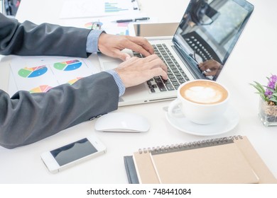 A man woring at business office desk with laptop, paper analysis and coffee. - Shutterstock ID 748441084