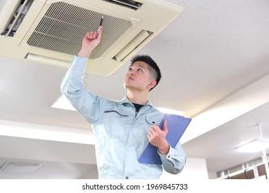 A Man In Work Clothes Doing Maintenance On The Air Conditioner