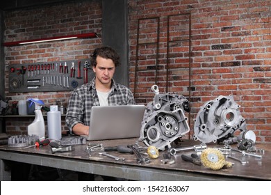 Man Work With Computer Search In Internet Spare Engine Parts On The Workbench In Home Garage Workshop, Diy Concept