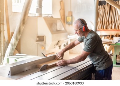 Man at work cutting timber on a sliding table saw - Powered by Shutterstock