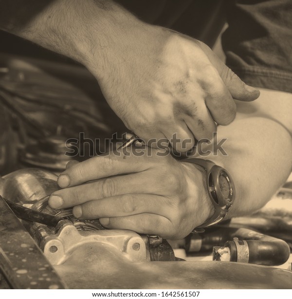 Man at work in a garage. Auto mechanic worker in car\
repair service. Image of mechanic hands with a tool. Auto repair\
concept. Close up. Black White vintage. Nice background for your\
text. Matte 
