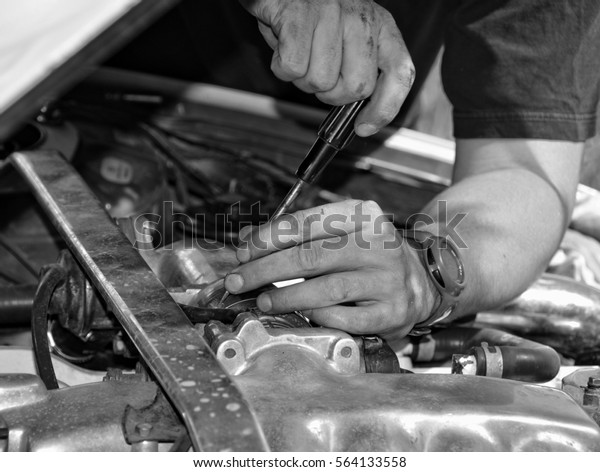 Man at work in a garage. Auto mechanic worker in car
repair service. Image of mechanic hands with a tool. Auto repair
concept. Close up. Black White vintage. Nice background for your
text. Matte 