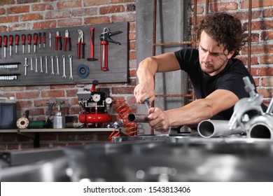 Man Work In Home Workshop Garage With Steel File Rasp, Filing Metal Pipe On The Workbench Full Of Wrenches, Diy And Craft Concept