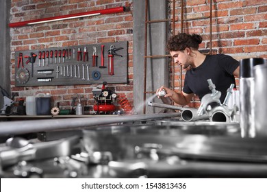 man work in home workshop garage with spray can paint metal pipe on the workbench full of wrenches, diy and craft concept - Powered by Shutterstock