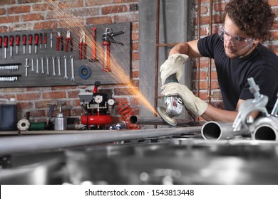 man work in home workshop garage with angle grinder, goggles and construction gloves, grinder metal makes sparks, diy and craft concept - Powered by Shutterstock