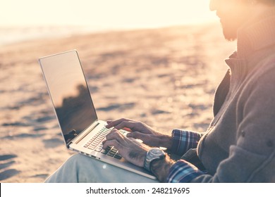 Man Work On Computer At The Beach At Sunset