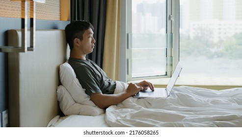 Man work on laptop computer on bed